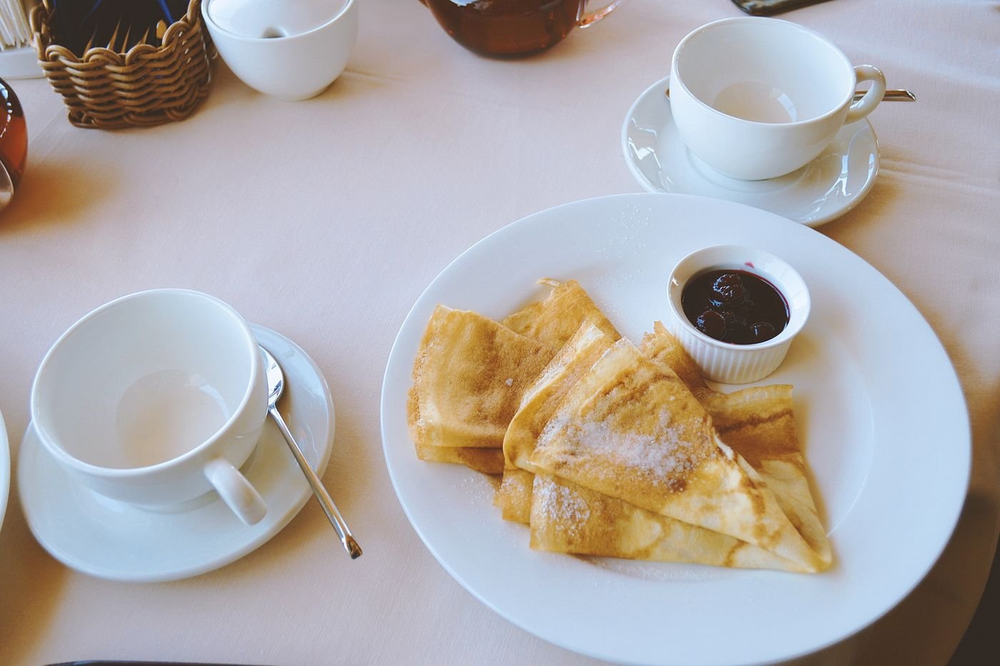 Folded French crêpes dusted with sugar, with a small dish of cherry jam