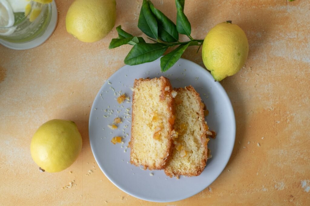 Two slices of a golden French yogurt cake on a plate, with lemons